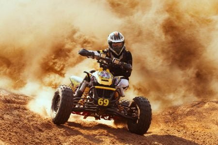 A driver is driving quad bike in desert